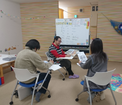 ホワイトボードを前にした講師と大人の受講生2人